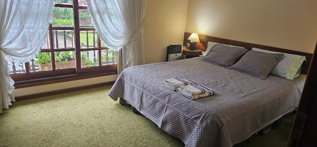 Dormitorio del departamento con cama matrimonial y ventana al jardín